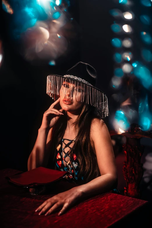 girl wearing a wide brimmed hat sitting down at a table