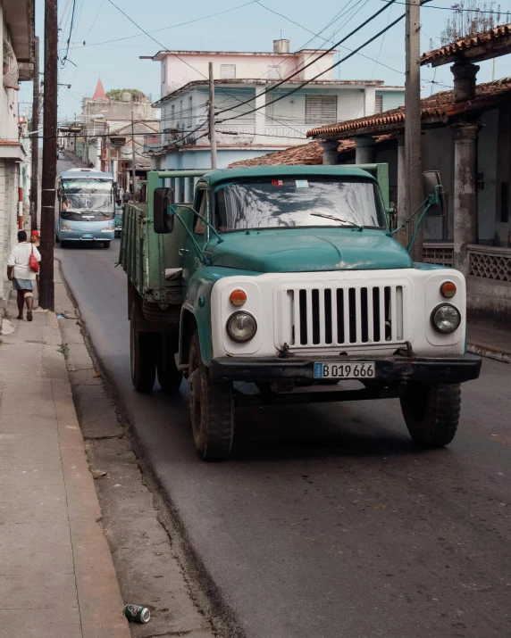 there is a green truck thats driving down the road