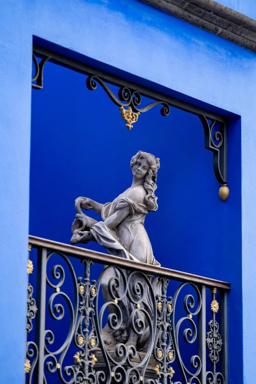 a statue on a balcony with a blue wall