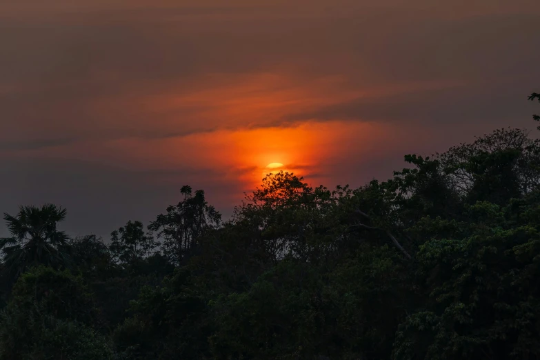 a very bright sun rising in the sky with thick clouds