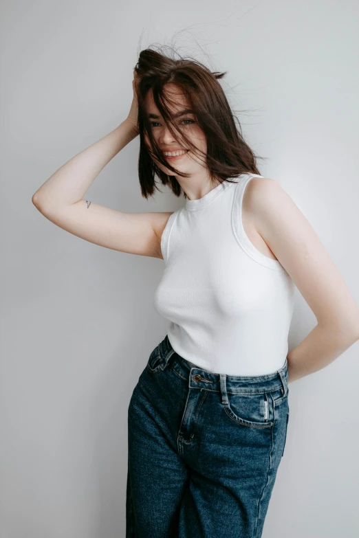 a woman posing wearing an white top and jeans