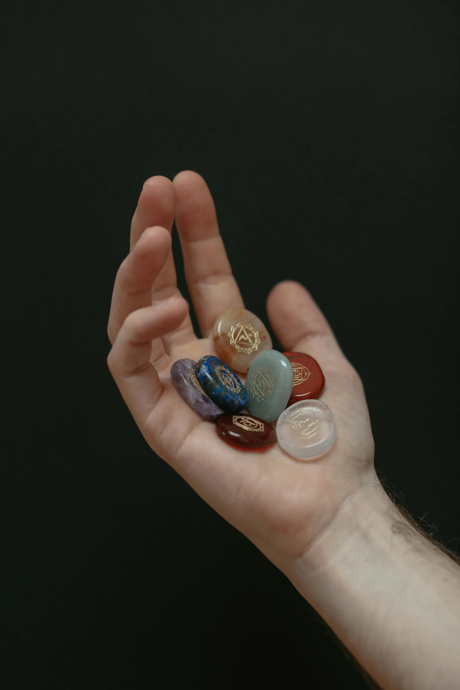 the small hand is holding five different round glass beads