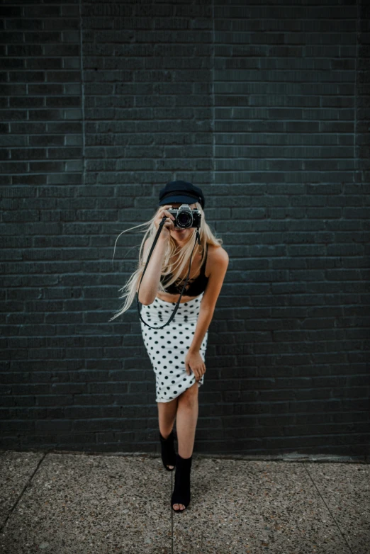 a woman wearing boots and a hat while standing on a sidewalk