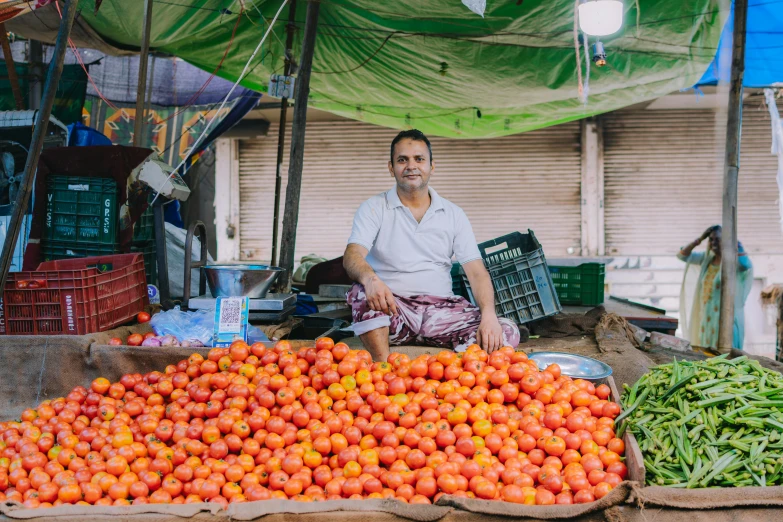 a man sits behind a pile of fruit in front of a display