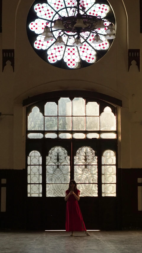 a woman standing in front of a large stained glass window