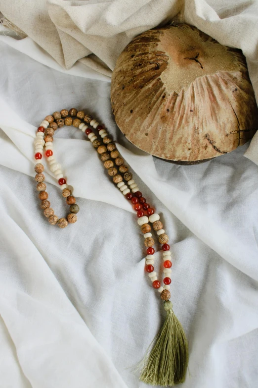 the beads on the beaded strand are sitting next to a piece of coconut