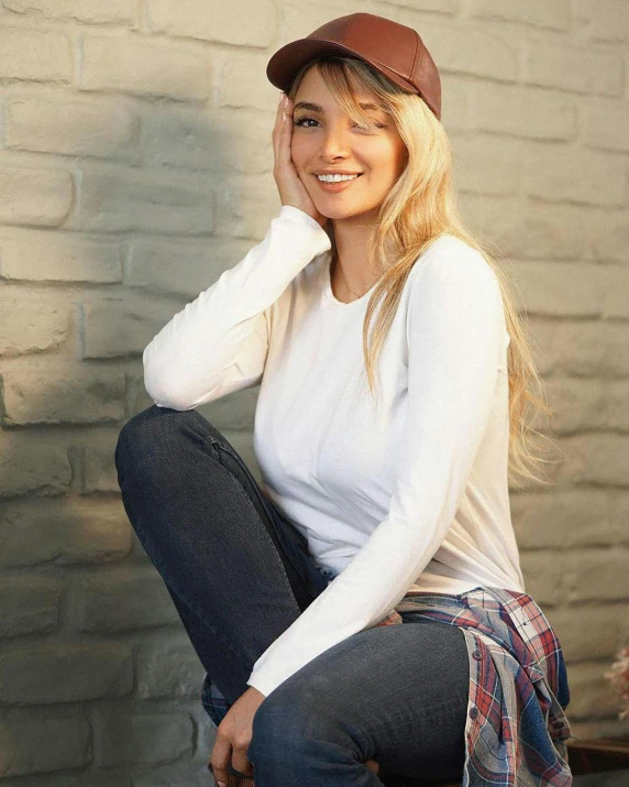 a woman is posing wearing a white shirt and jeans