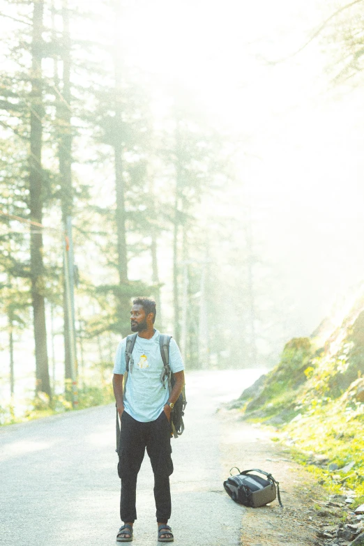 a man stands on the road with his back pack