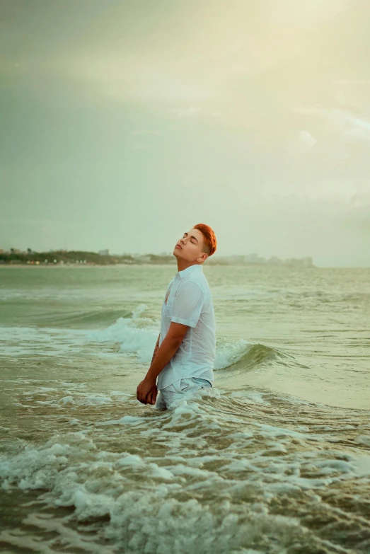 man in white shirt wading into the ocean