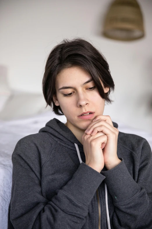 a woman is sitting down with her hands together