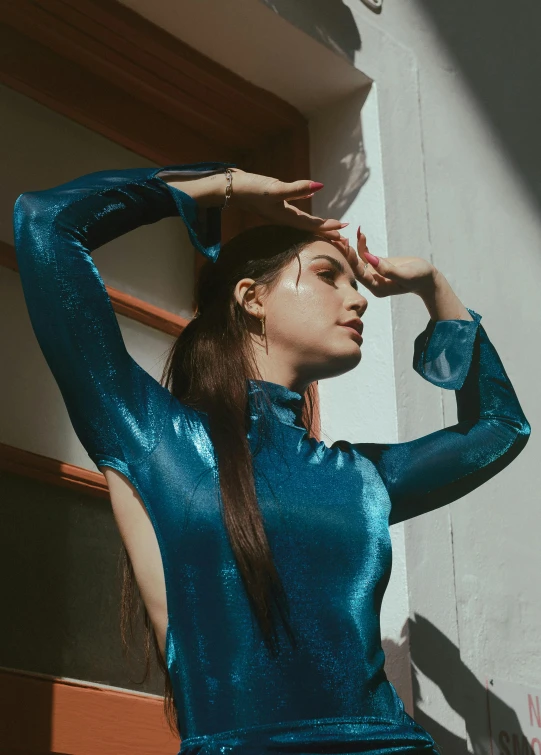 a young woman in a blue dress standing next to a building