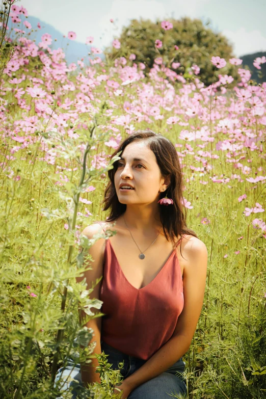 a beautiful young woman standing in a field of flowers