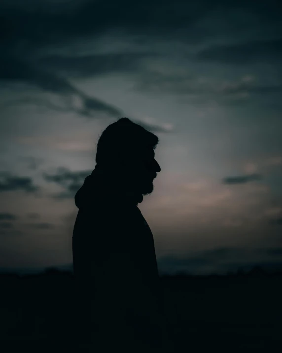 a silhouette man at dusk gazing in the distance