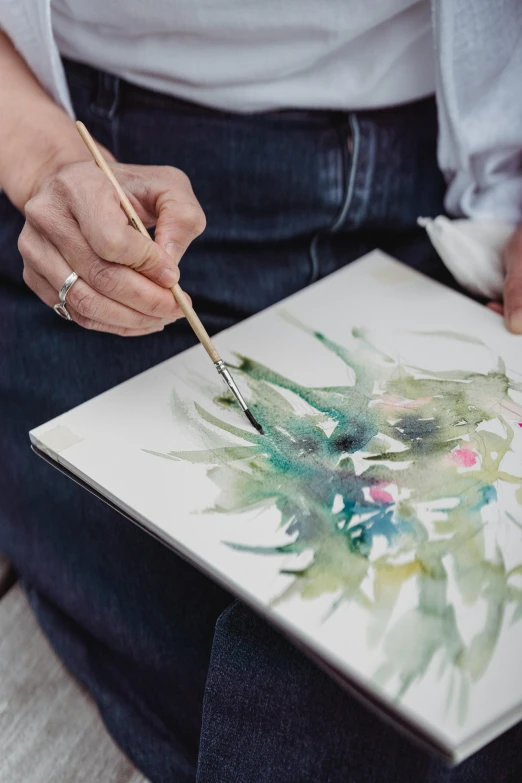 a person is painting a flower picture on canvas