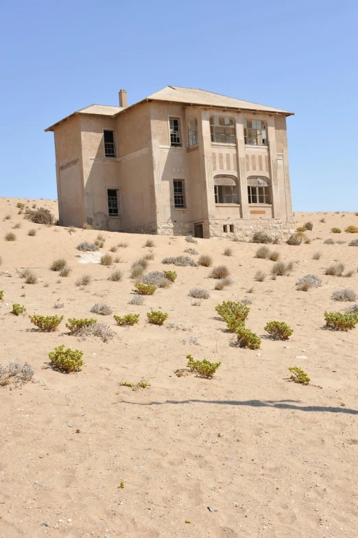 a person is standing outside a run down house in the desert