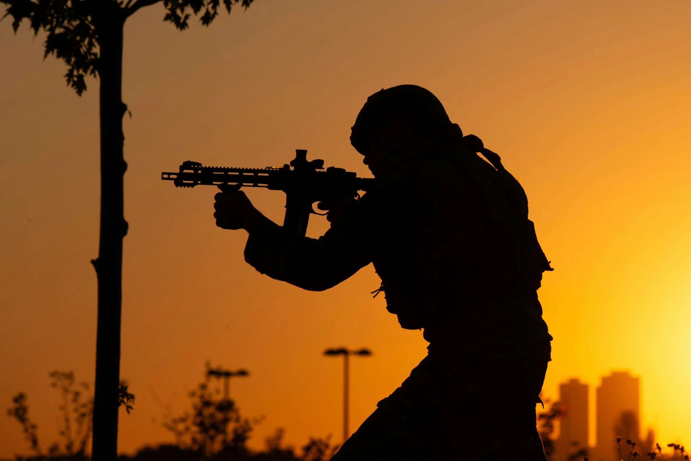 the man is holding a machine gun in silhouette