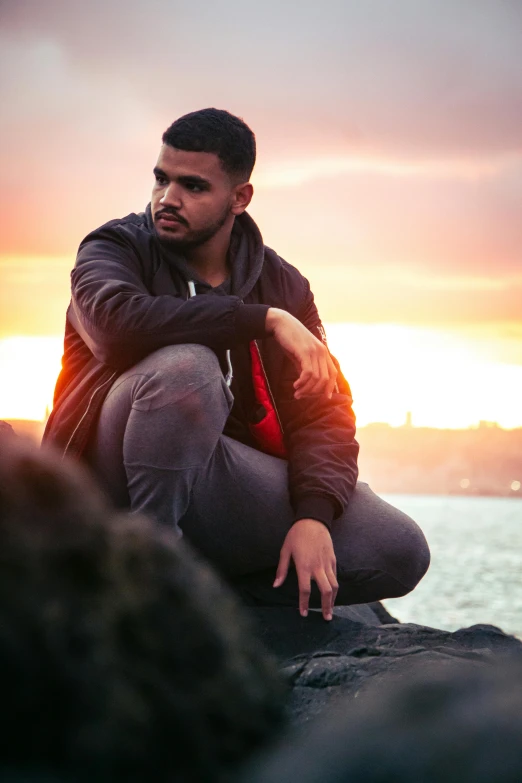 a man sitting on top of a rock near the ocean