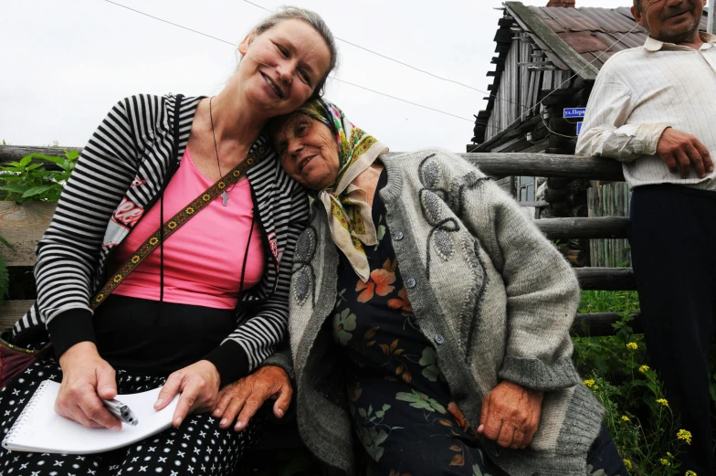 two woman are sitting and one of them is holding a paper