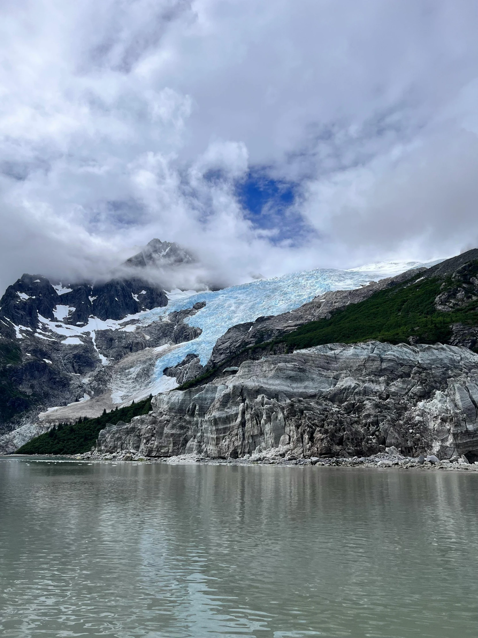 mountains and glaciers near water with cloudy sky