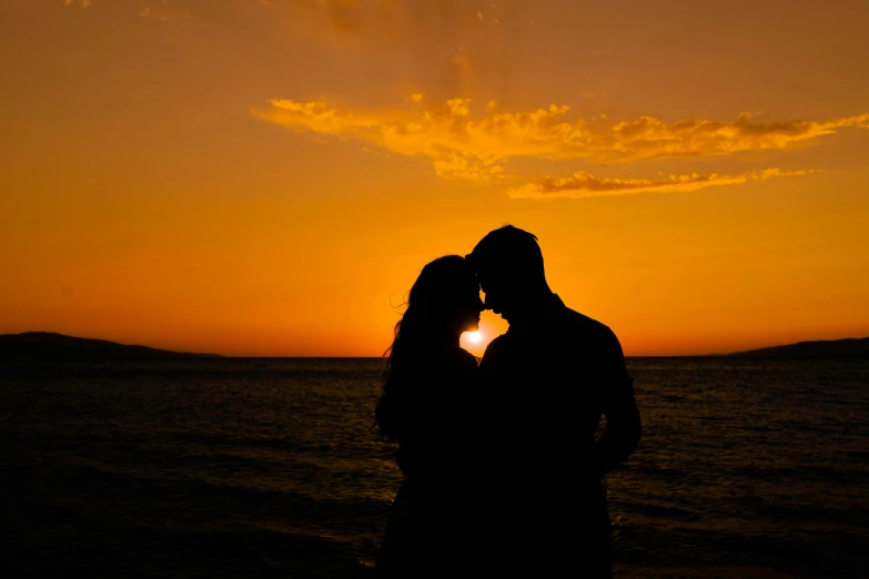 couple kissing on beach at sunset as the sun sets