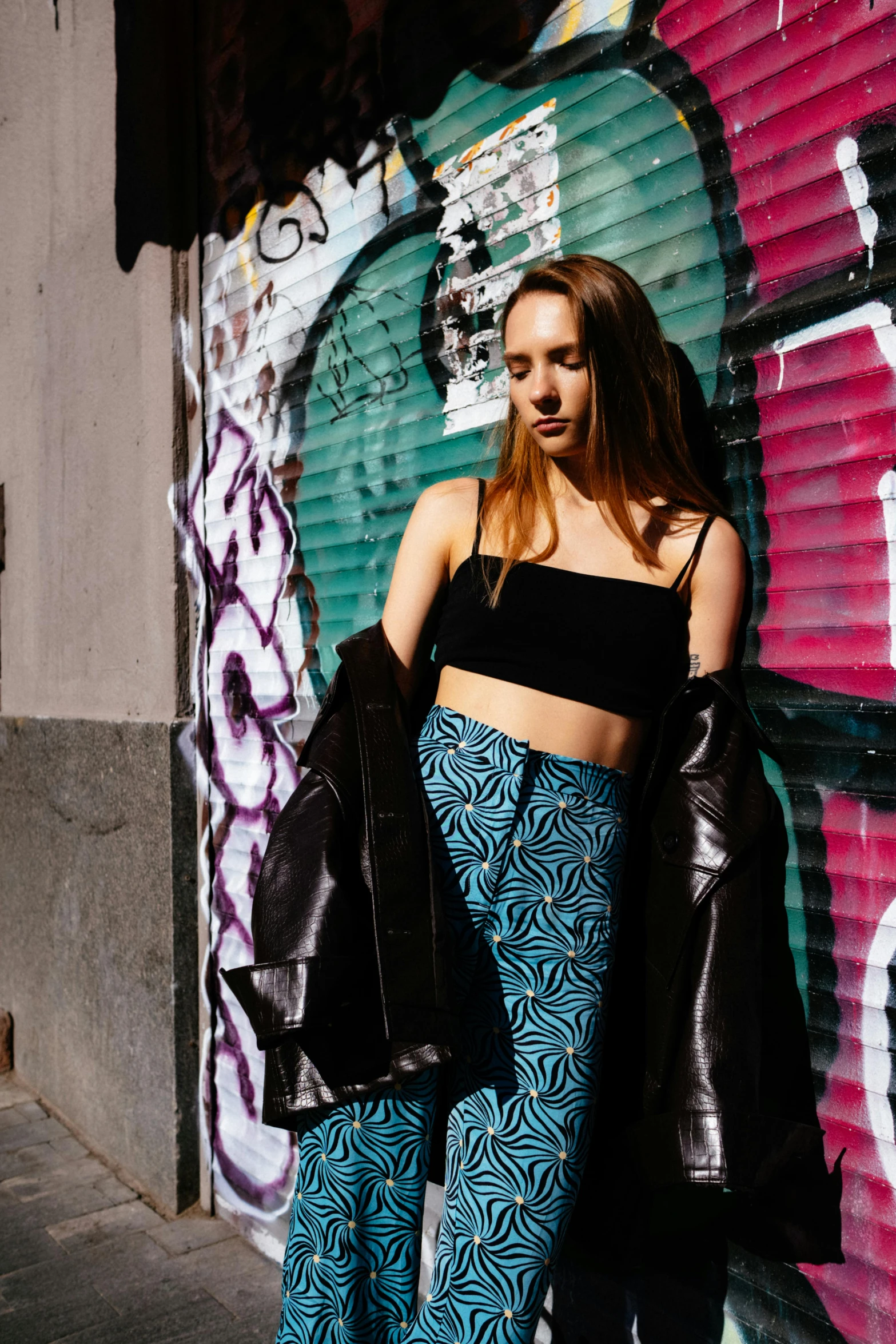 a beautiful young woman standing in front of graffiti