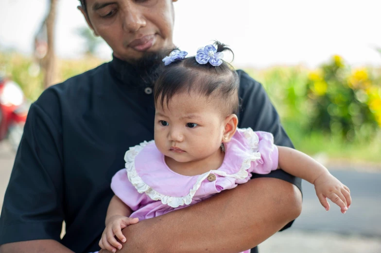 a person holding a small child wearing a purple dress