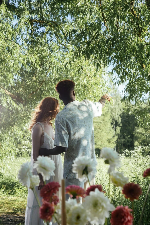 a man and woman holding flowers in a forest