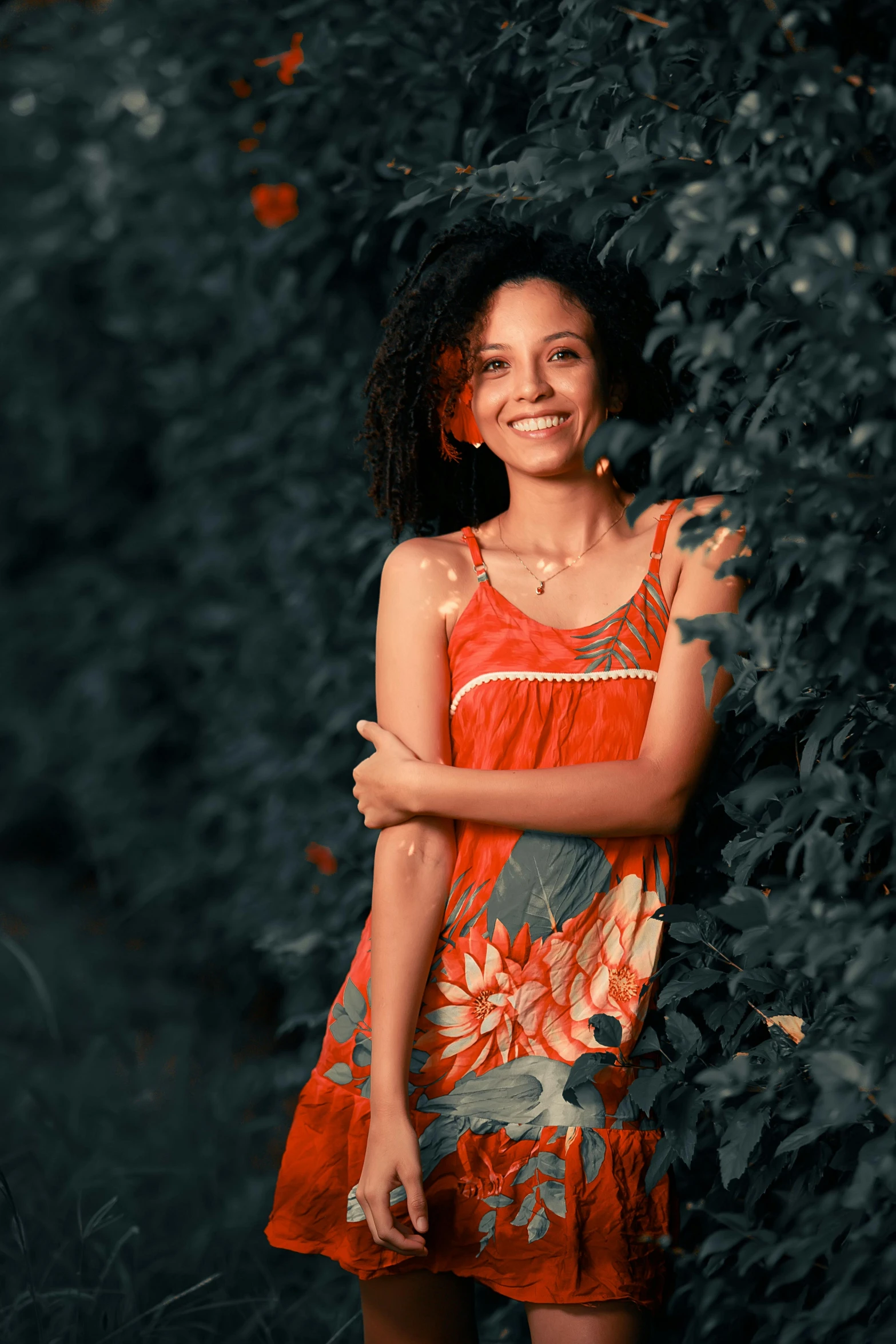 a beautiful woman standing near a hedge in a dress