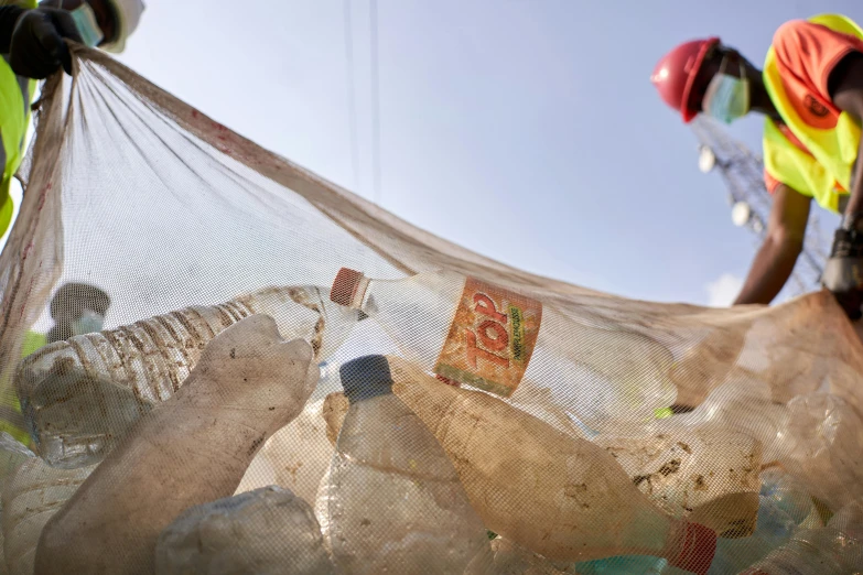 workers prepare to clear up plastic trash as they use net