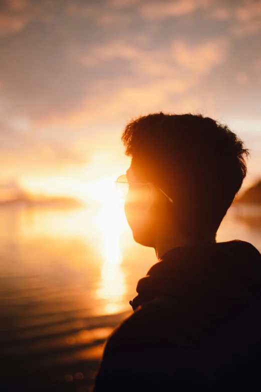 the shadow of a man with glasses and the sun peeking over his shoulder