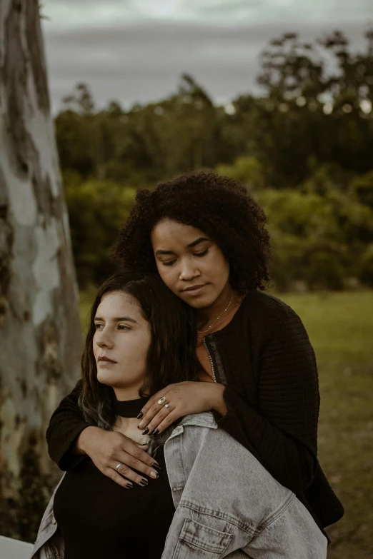 a woman leaning on another women shoulder in an outdoor area