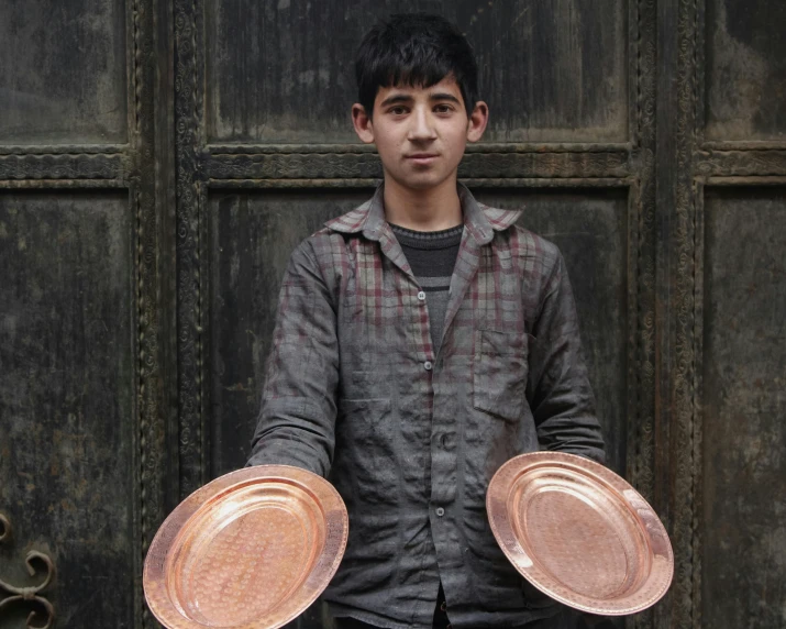 a man holding two plates in front of a wooden wall