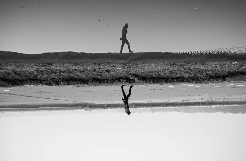 a person walking in front of water and sand