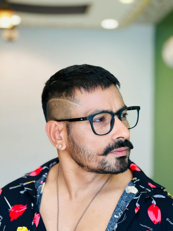 a man wearing glasses and a black floral shirt