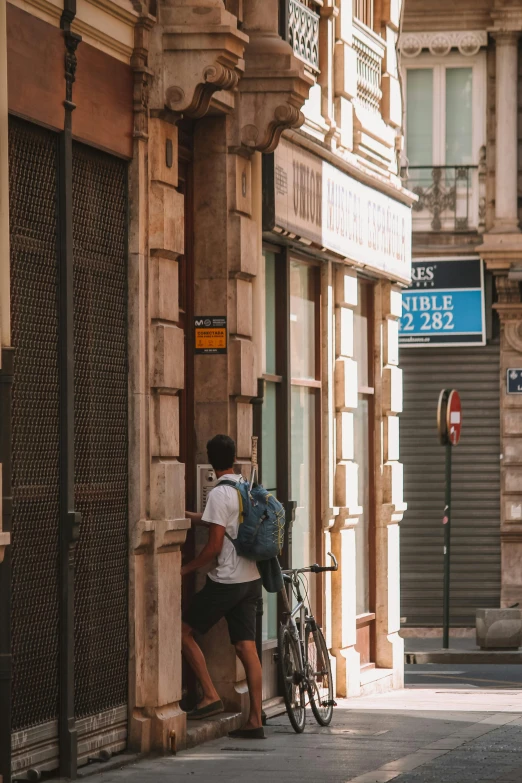 a man standing next to a building with a bicycle