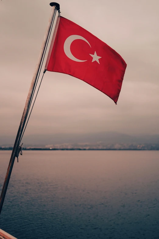 a turkish flag hanging on the side of a boat in the water