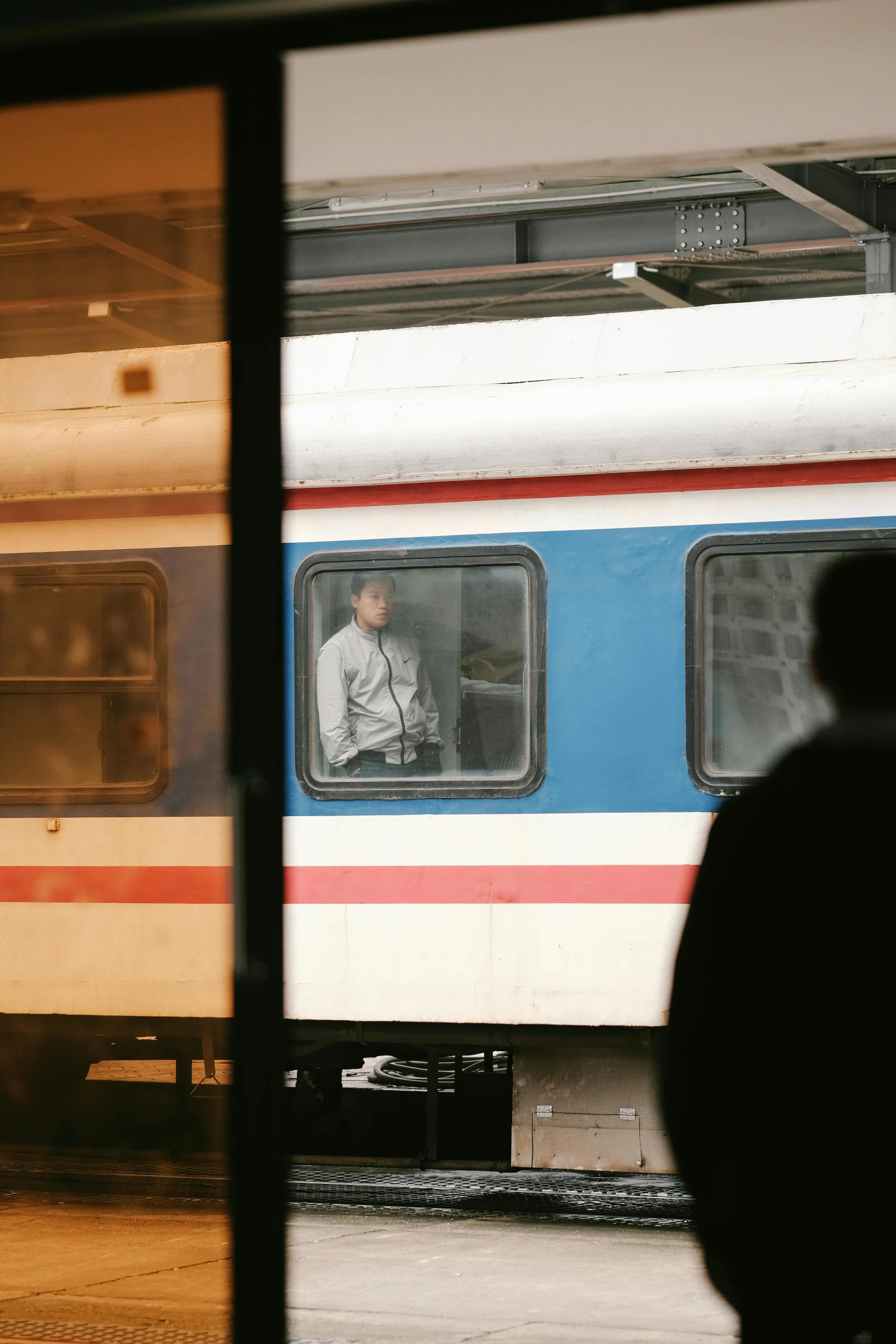 a person standing in a train window while looking out the window