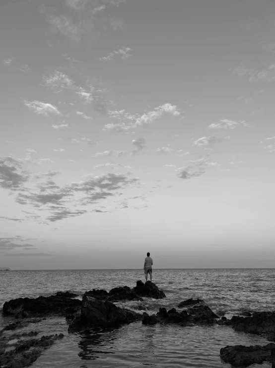 a person stands on rocks overlooking the ocean