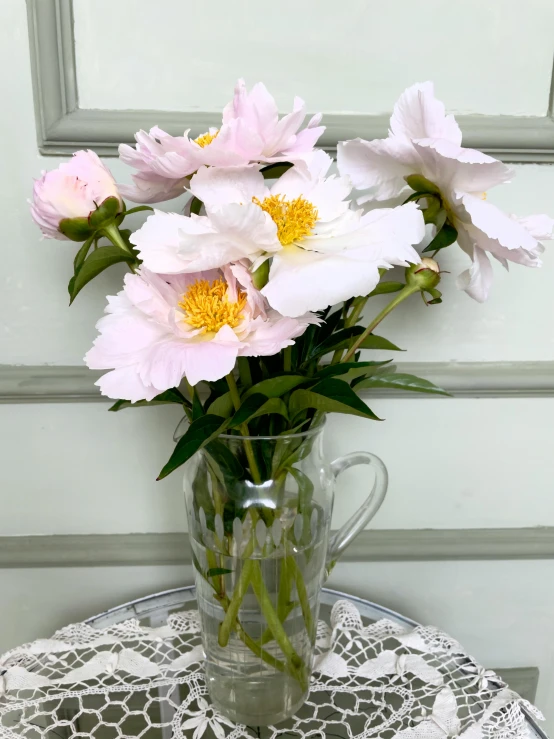 a clear vase on a doily filled with flowers