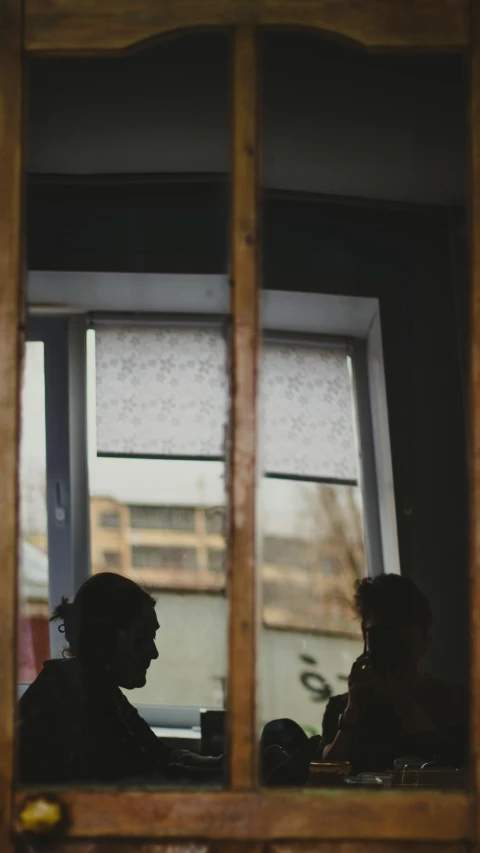 two people sitting next to each other with one reflection in the window