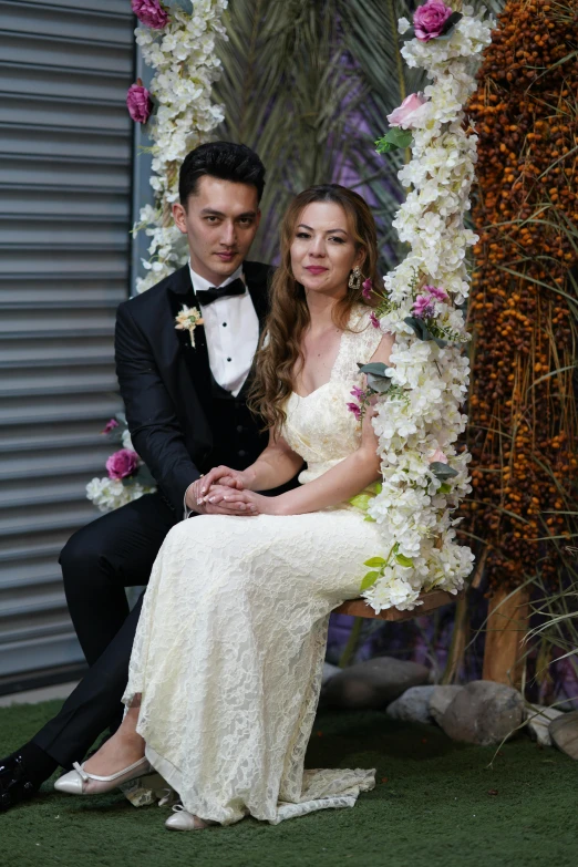 a newlywed couple posing in front of flowers and arch