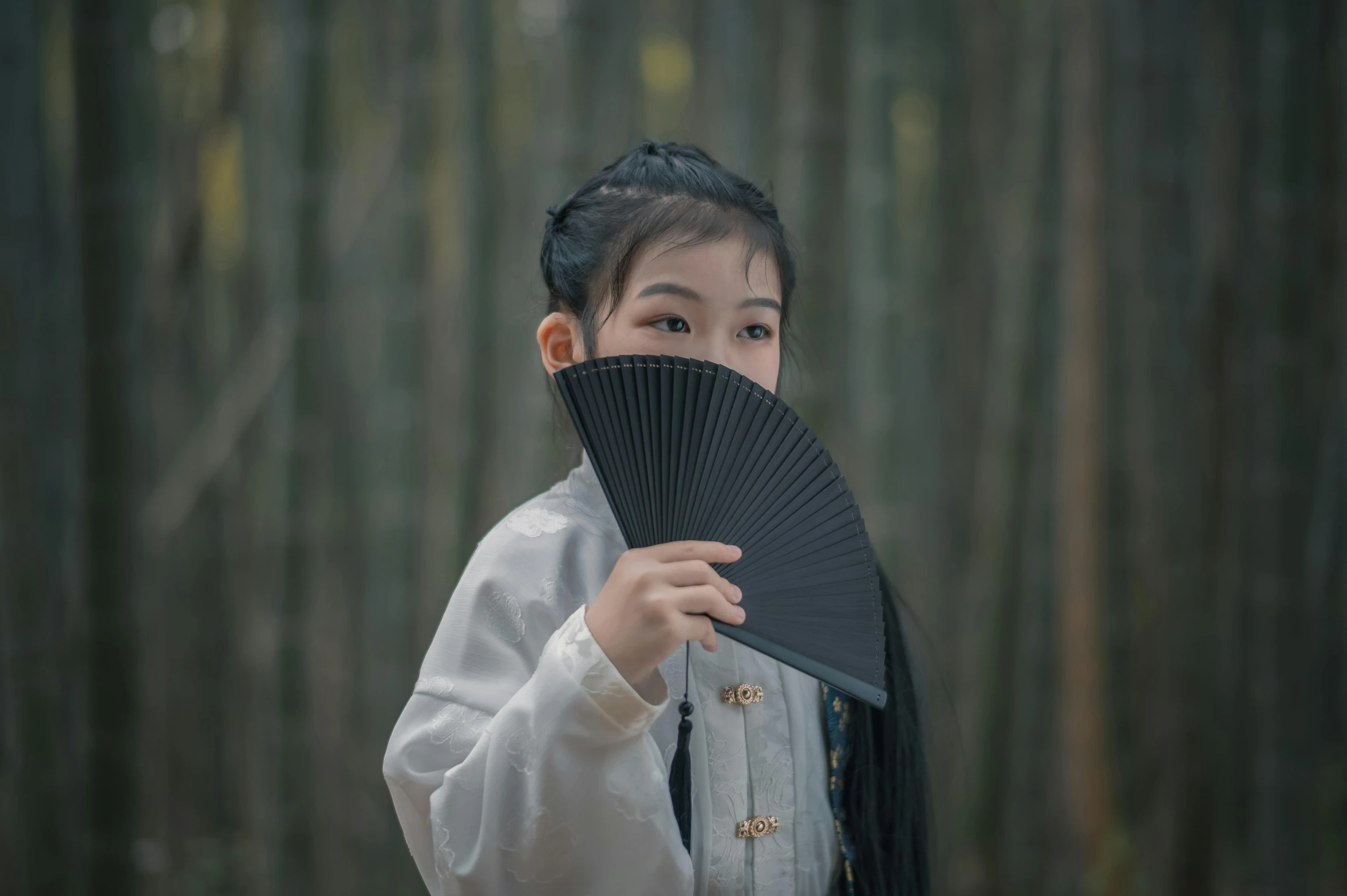 young asian woman holding a black fan in her hand