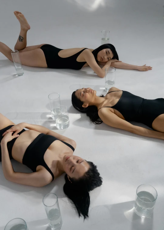 three women in black bathing suits laying down with drinks