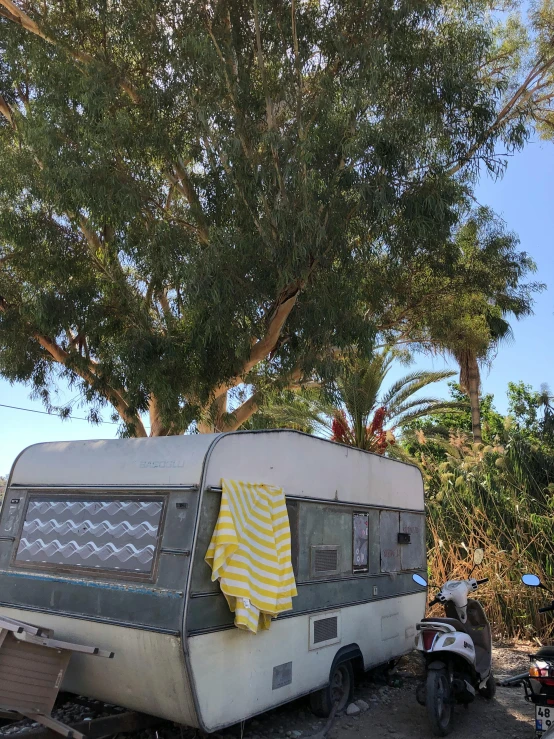 a camper trailer that has a yellow striped towel hanging outside