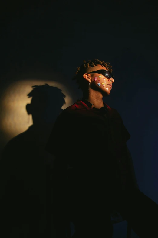 a man standing against a wall in the dark