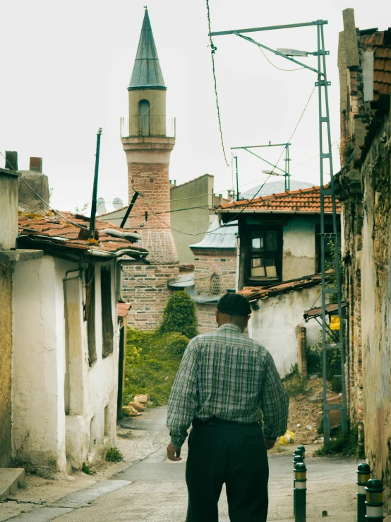 a man in plaid shirt walking down street next to buildings