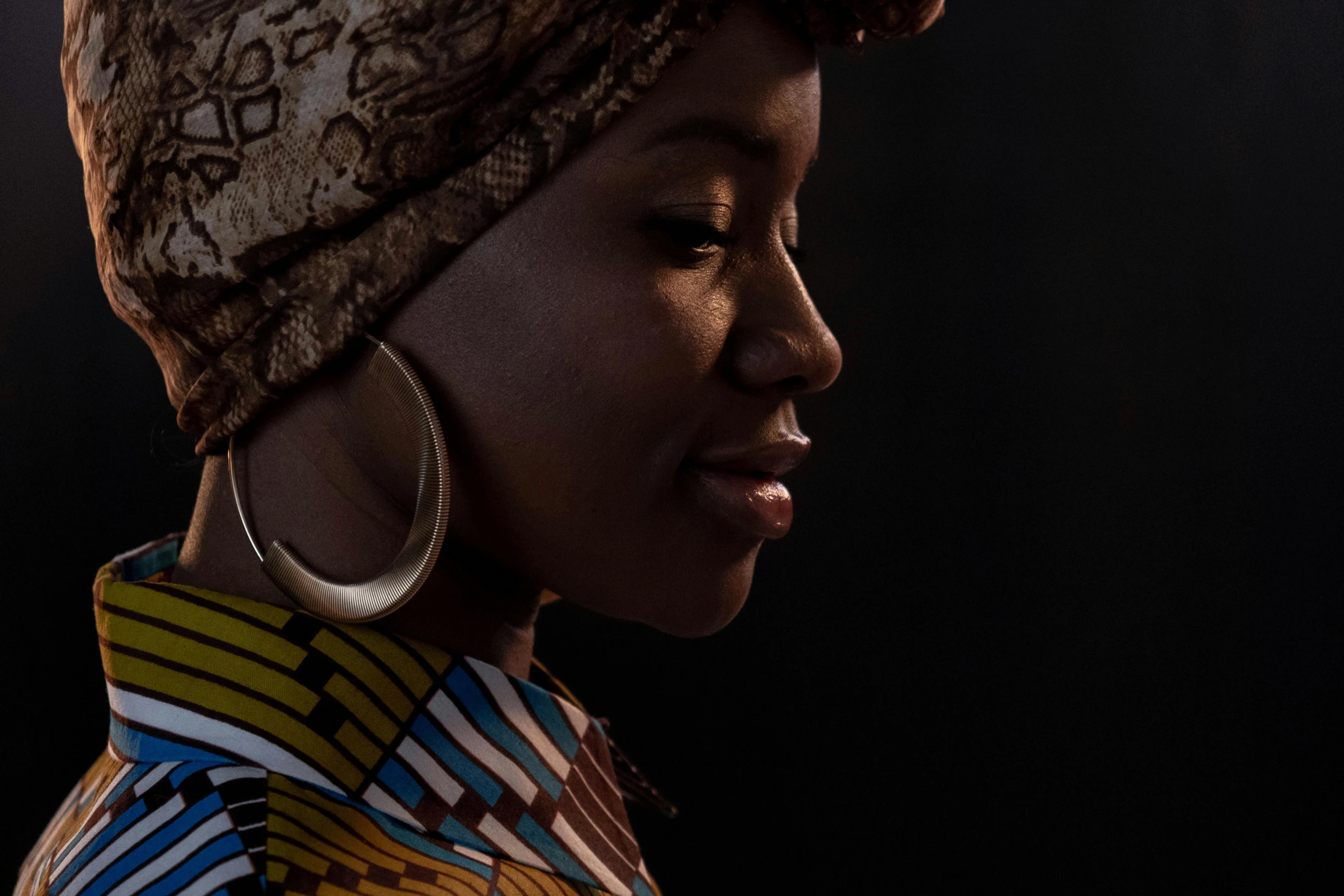 a woman wearing large hoop earrings with a scarf on her head