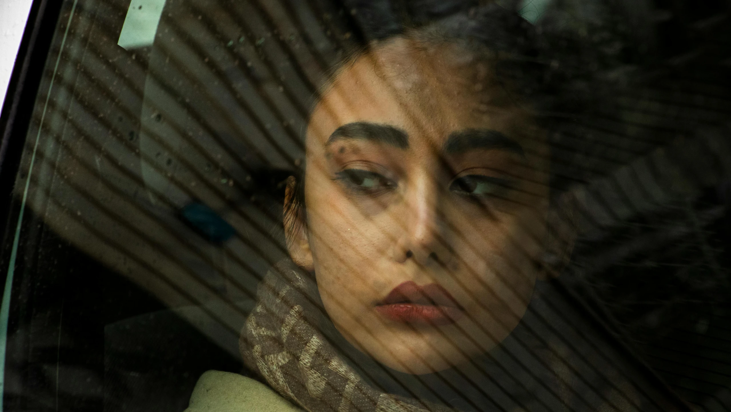 a woman looking in a car mirror behind a window