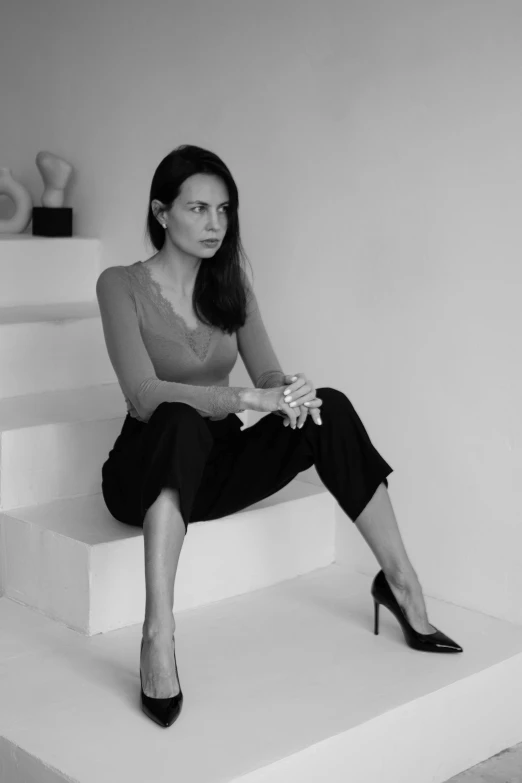 a woman in a black skirt and heels sitting on a step