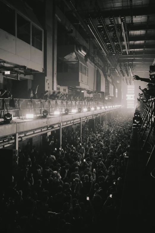 an audience looks on from the second story of a building as workers work on the production line